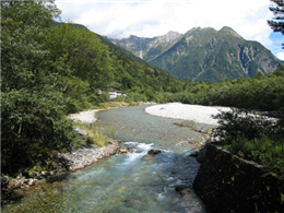 上高地梓川清澈透明的溪流，背後是北阿爾卑斯連峰的明神岳(2,931公尺)及新穗高岳(3,090公尺)